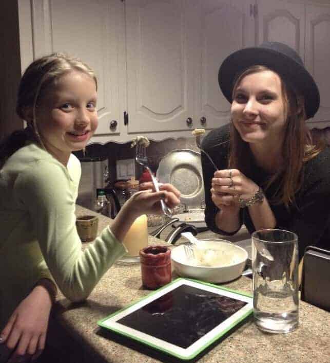 Anecia's daughter and her friend holding forks at a kitchen counter