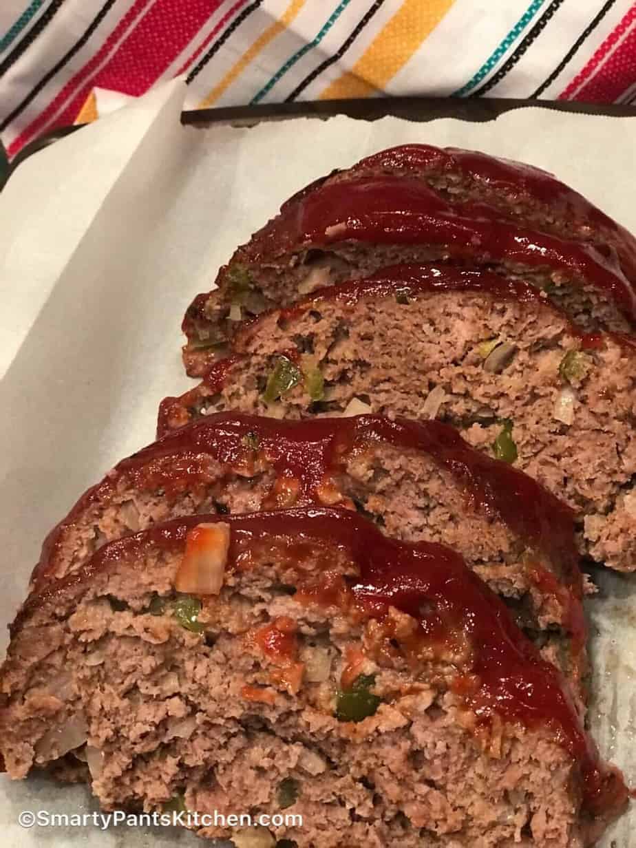 Sliced meatloaf with tomato sauce on a white platter