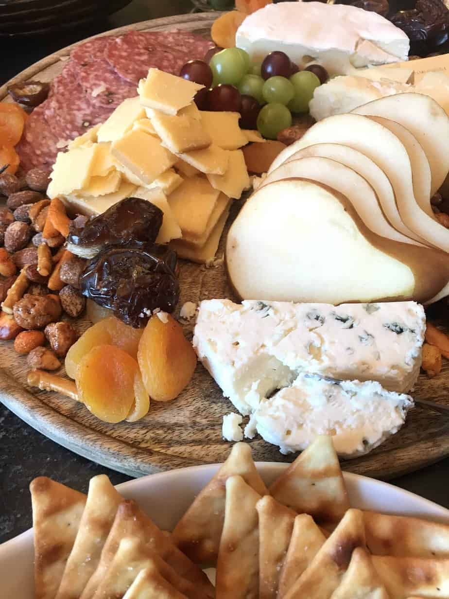 Cheese board with variety of cheeses, nuts, dried fruit and olives on a wooden board