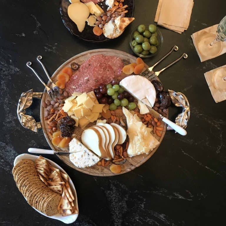 Variety of cheese, meats and nuts on wooden board