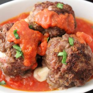 Mozzarella stuffed meatballs drizzled with red sauce.