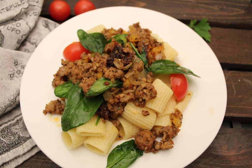 Italian Skillet Supper on a white plate with spinach leaves and cherry tomatoes