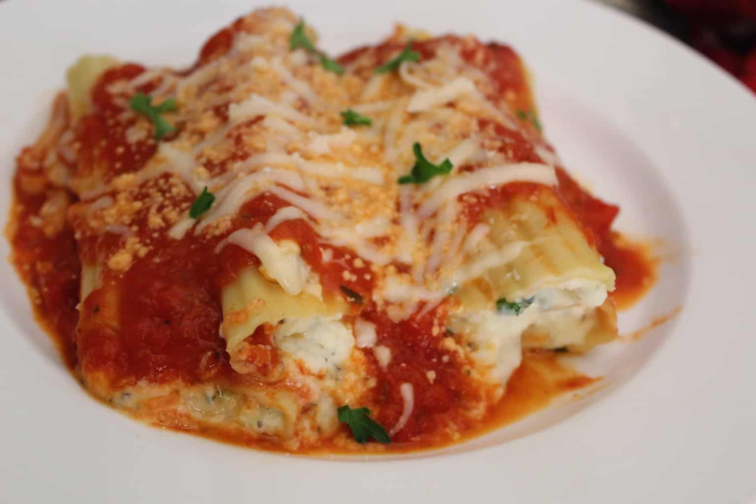 Savory ricotta and mozzarella stuffed Manicotti shells on white plate