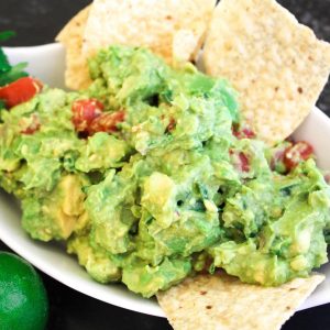 Guacamole in a white serving bowl with chips.