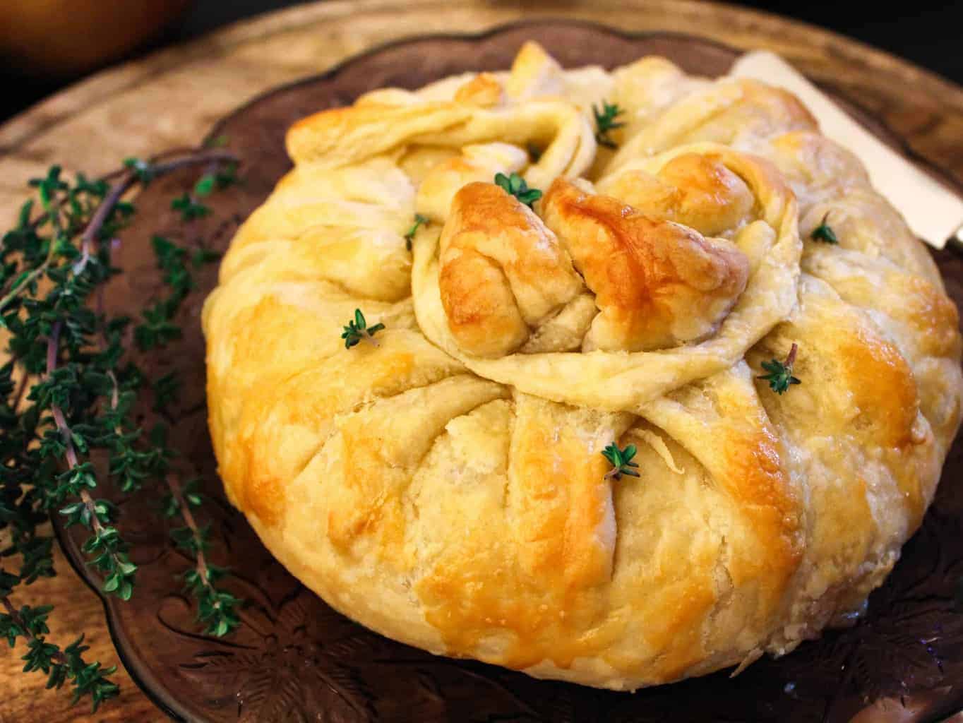 Brie en croute on purple plate garnished with thyme