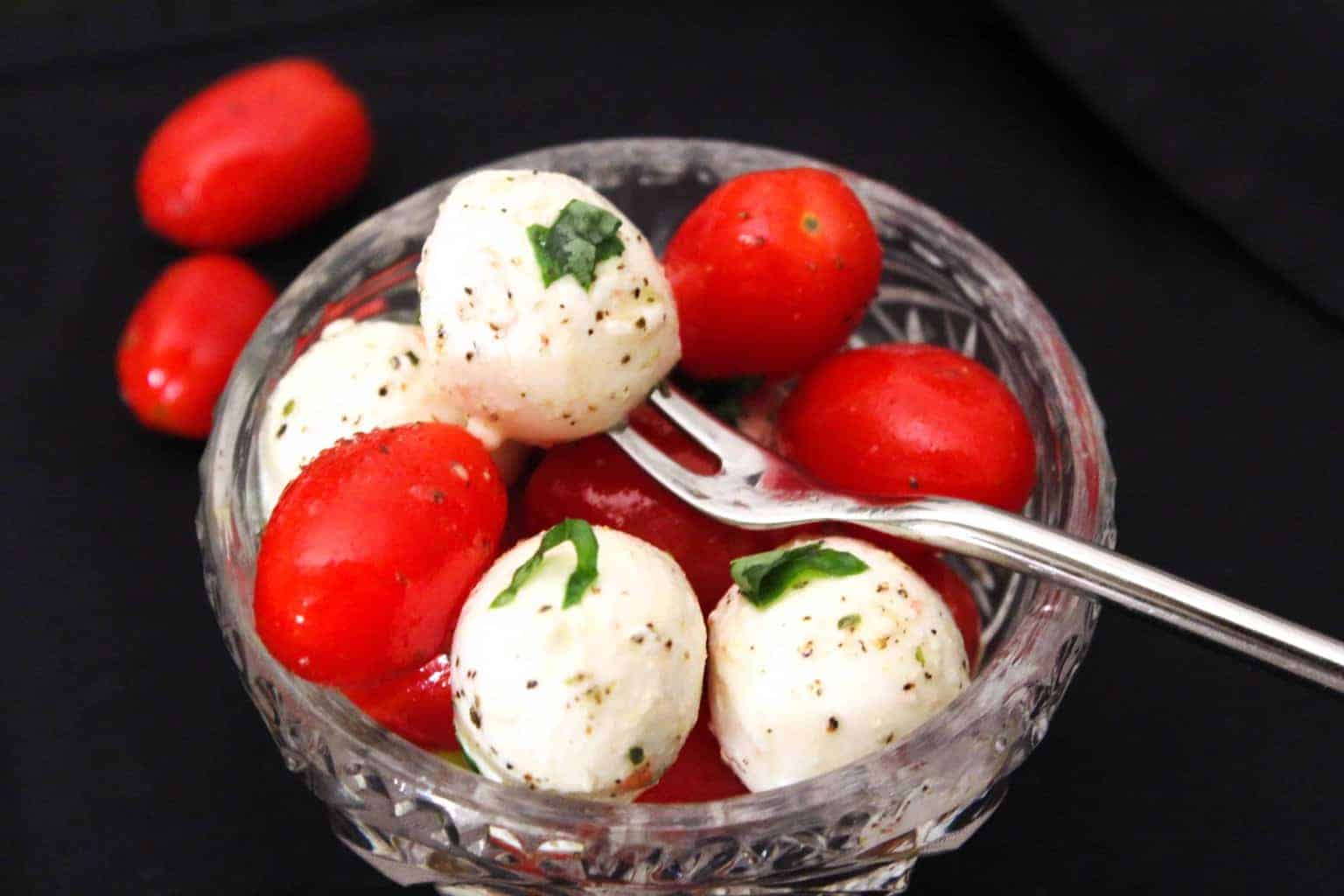 Caprese Salad in glass bowl garnished with fresh basil.