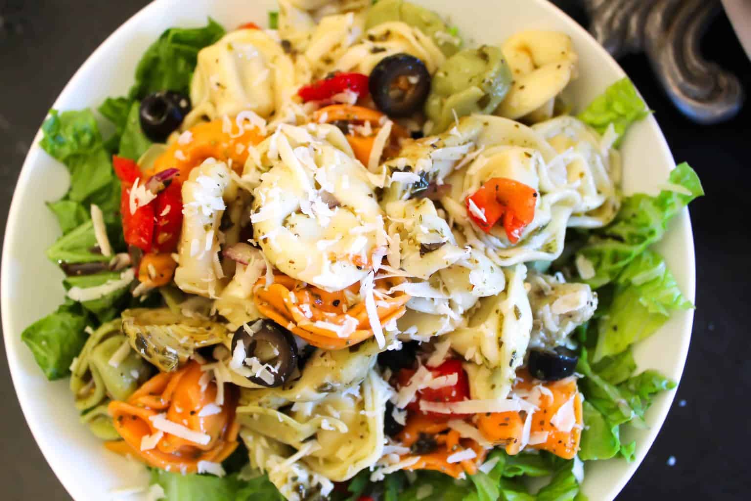 Tortellini Pasta Salad in a white bowl on a bed of green lettuce