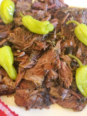 Shredded Mississippi Pot Roast with pepperoncini on white plate