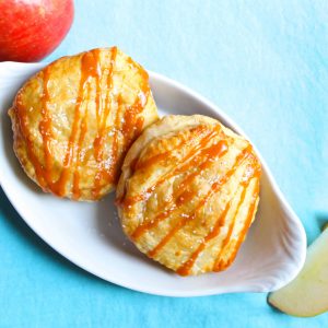 Two puff pastry hand pies drizzled with caramel sauce on a white plate