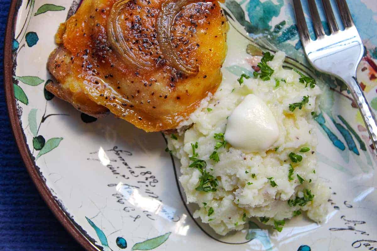 Oven baked chicken thigh and mashed potatoes on decorative plate