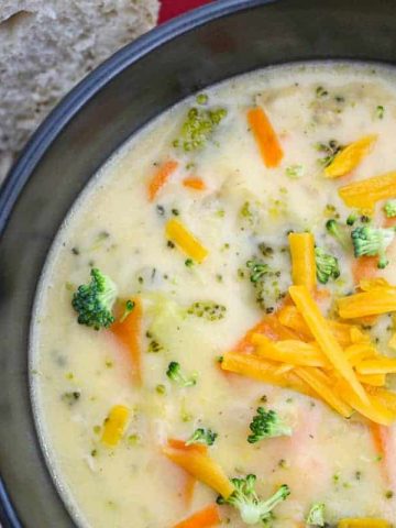 Organic Broccoli Cheese Soup in black bowl garnished with shredded cheese