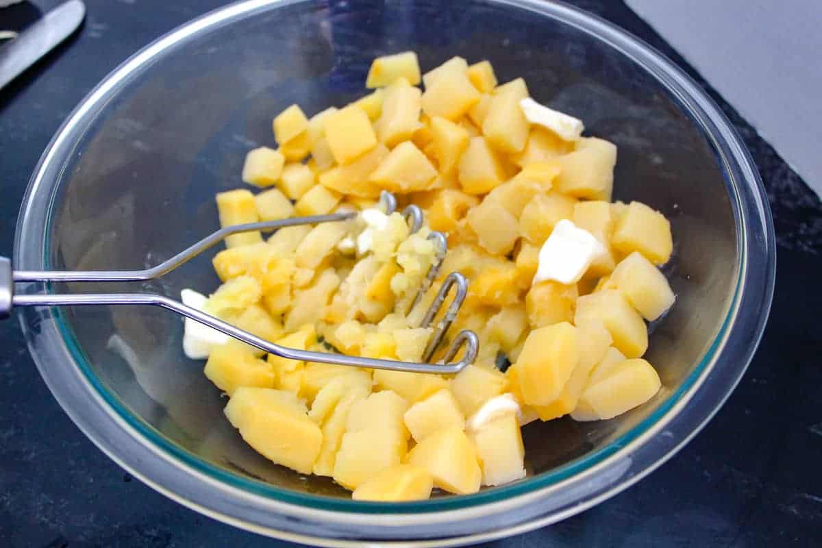 Bowl of cooked rutabagas being mashed 