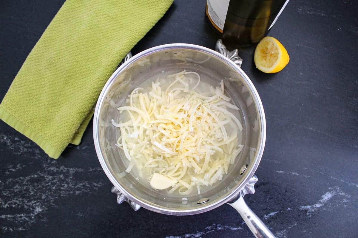 Shredded cheese in saucepan with lemon on the side