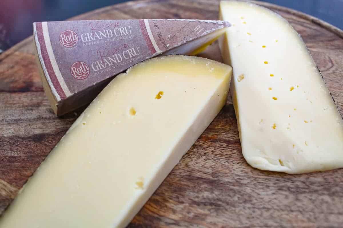 Three triangles of cheese on wooden board.