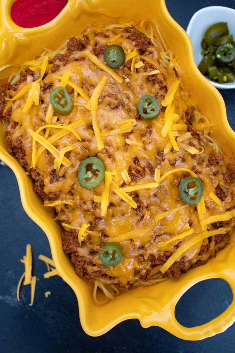 Chili Spaghetti Casserole topped with jalapeno slices in a yellow scalloped bowl.