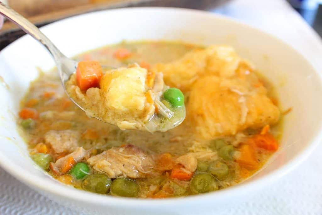 spoonful of chicken pot pie over a bowl of soup with submerged pastry
