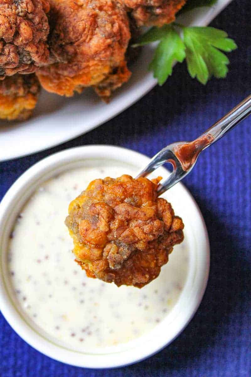 Holiday Sausage Ball on fork resting over honey mustard dip