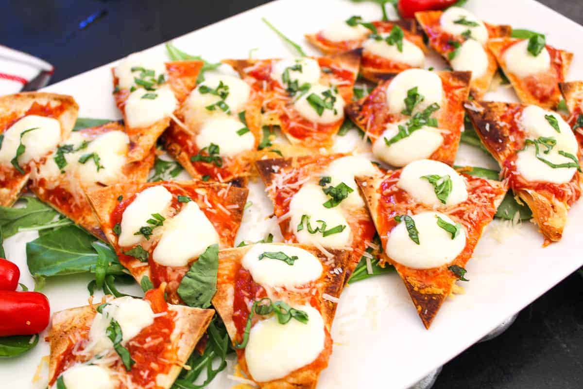 Margherita Nachos on white serving platter with fresh basil.