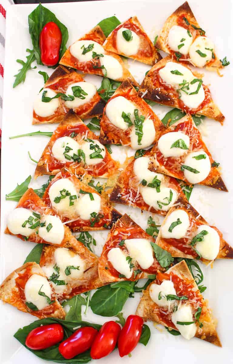 Margherita Nachos cut into triangles on a white serving platter.