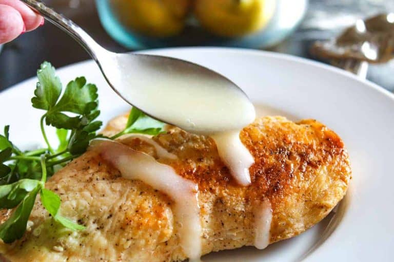 Lemon sauce being spooned and drizzled over chicken breast