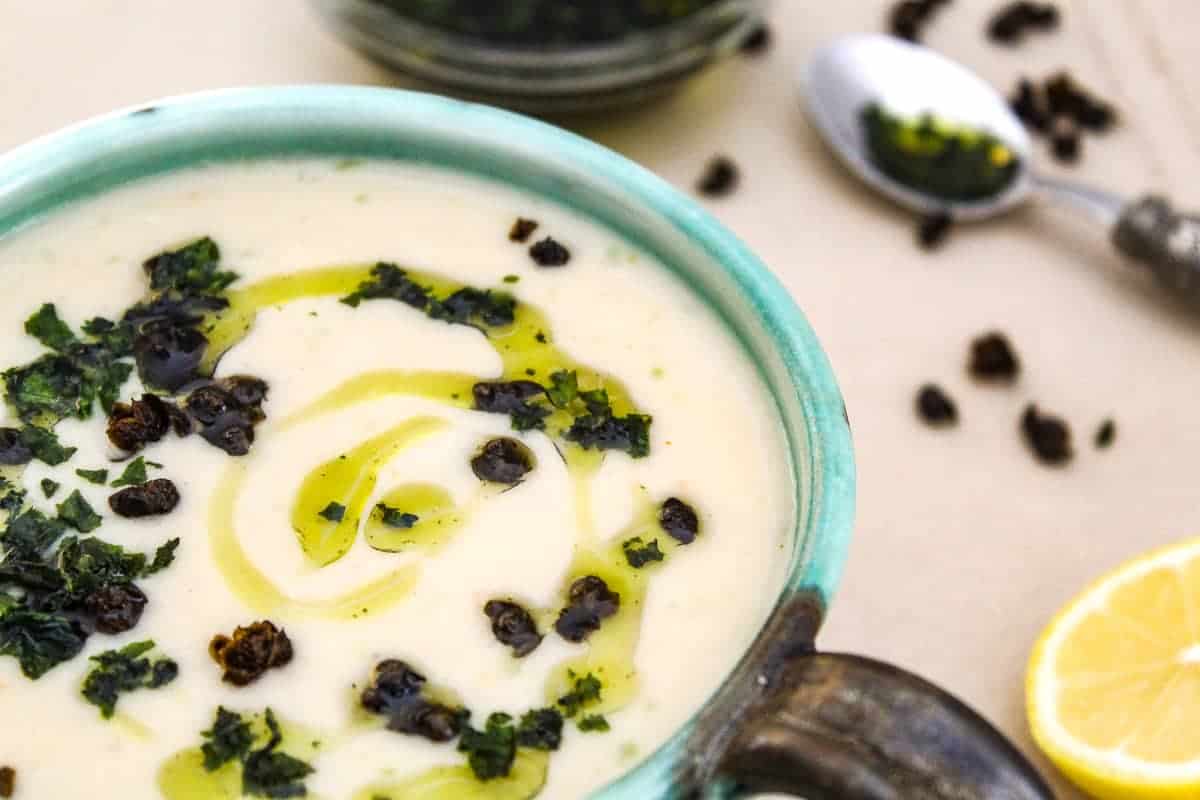 Soup in green bowl garnished with oil and thyme.