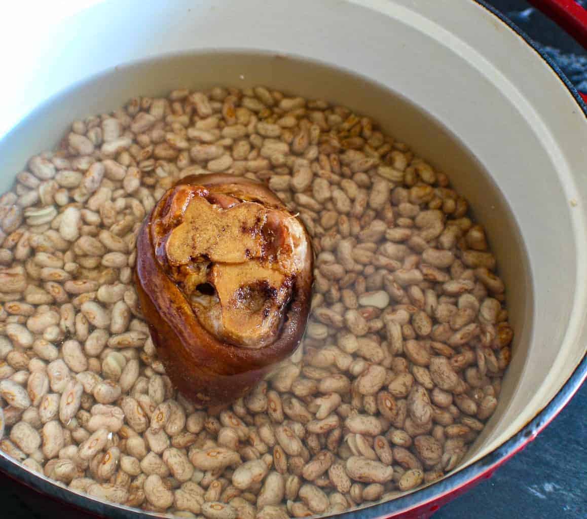 Dried pinto beans in a stockpot with water and a smoked ham hock.
