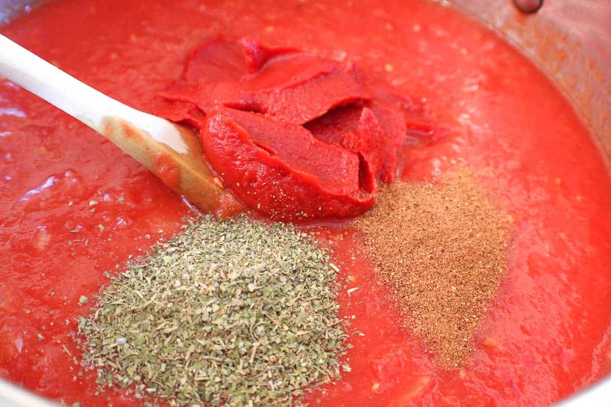 Dried Italian seasonings in sauce.