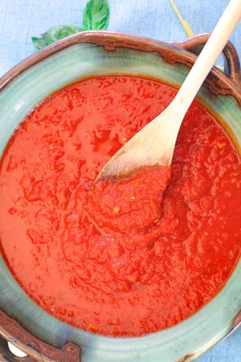 San Marzano sauce in green bowl with wooden spoon.