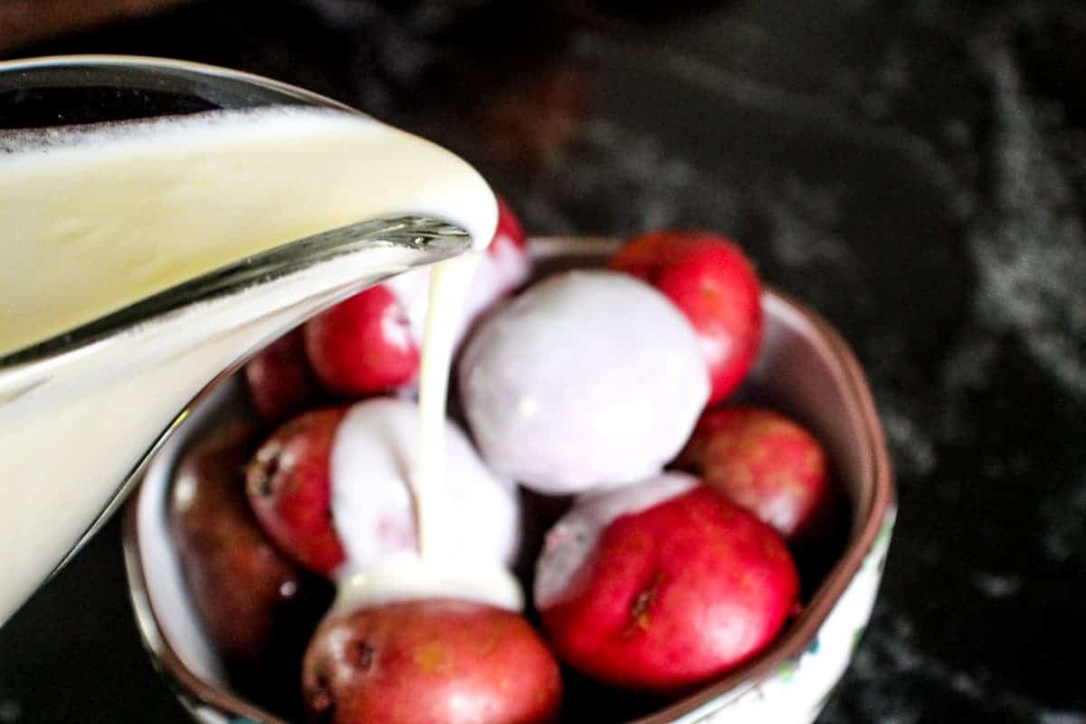 White sauce being drizzled over red new potatoes