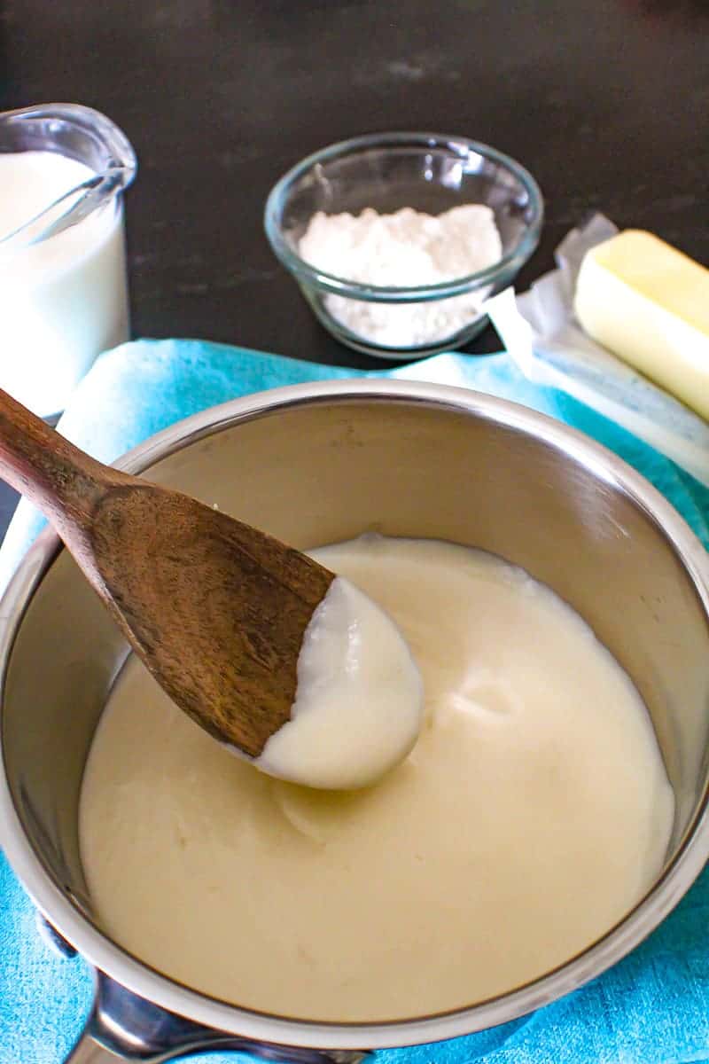 Basic White Sauce in pan with a wooden spoon