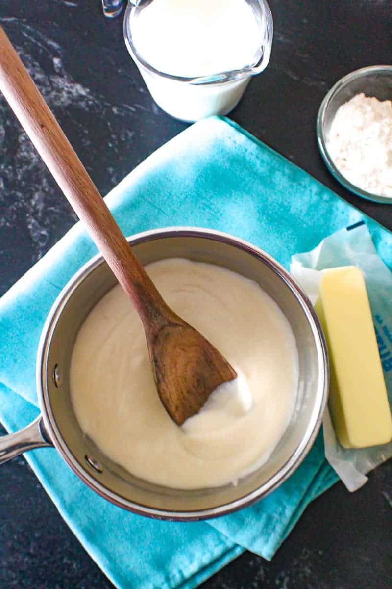 White cream sauce in pan with wooden spoon.