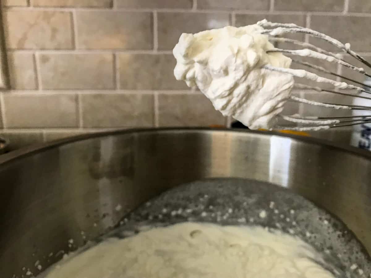 Whipped cream forming a stiff peak on a wire whisk