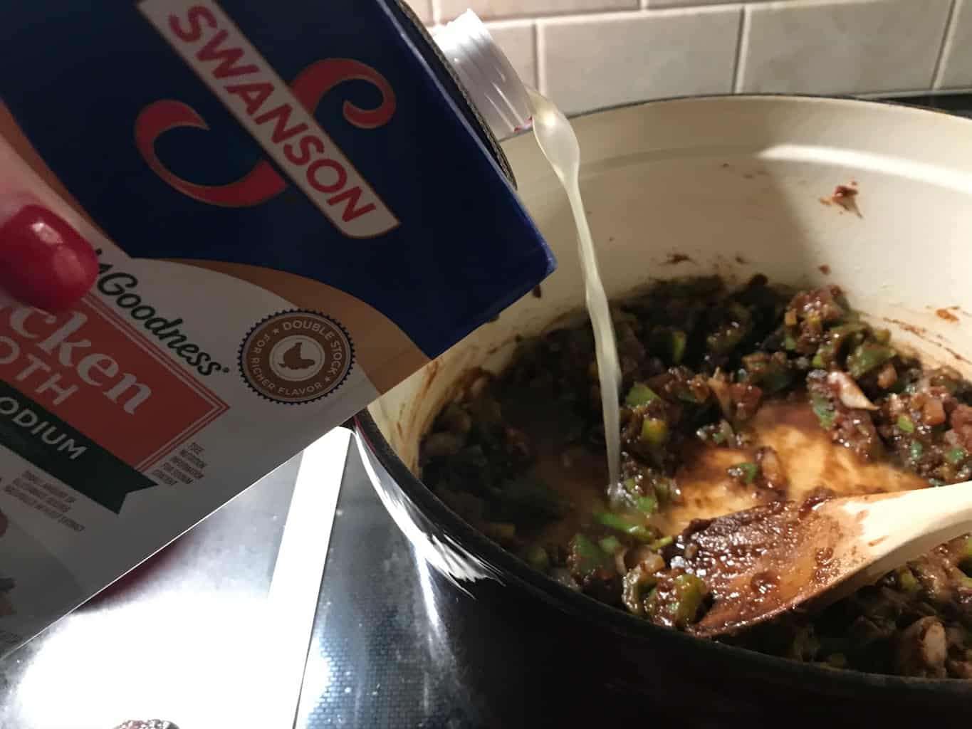Chicken broth being added to stockpot.
