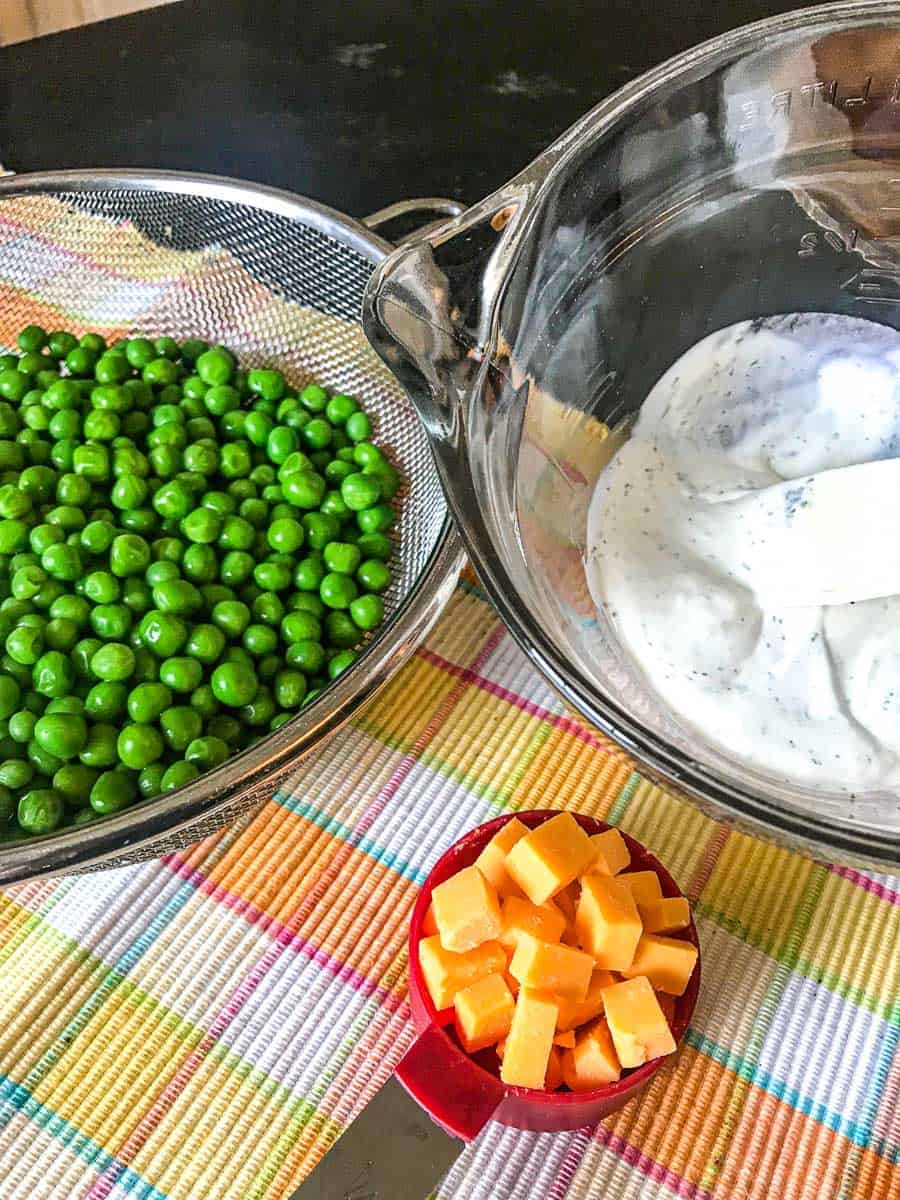 Peas in strainer with cubed cheddar and sauce on the side