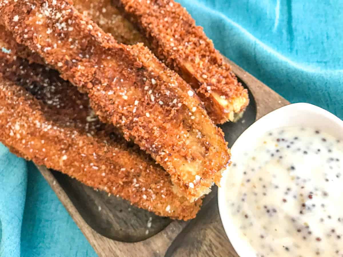 Strips of fried eggplant sticks on a wooden plate