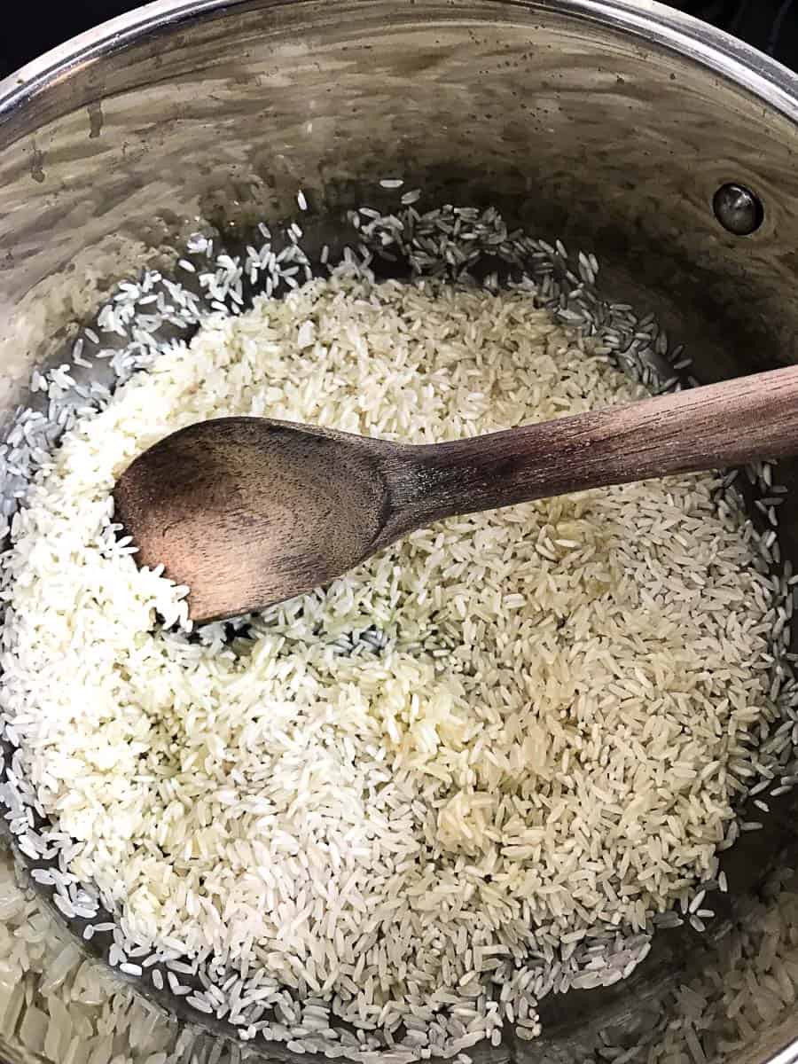 White rice in stockpot with wooden spoon