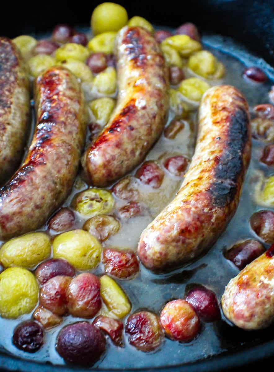 Balsamic vinegar, sausage and grapes in cast iron skillet.