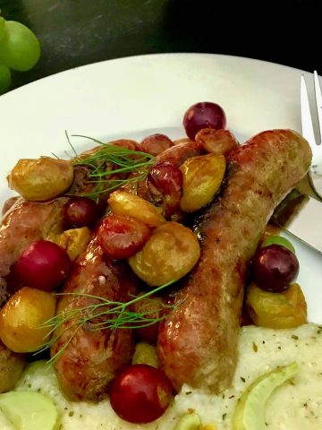 Italian sausage links and roasted grapes on white plate