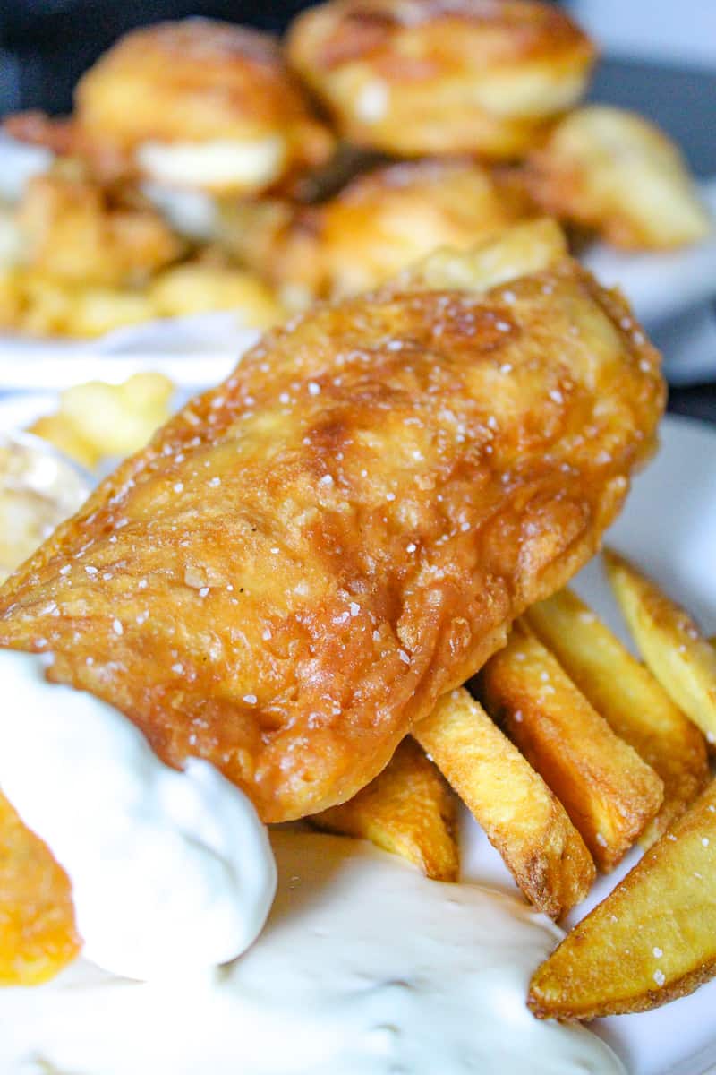 Fried fish filet garnished with kosher salt sitting on french fries