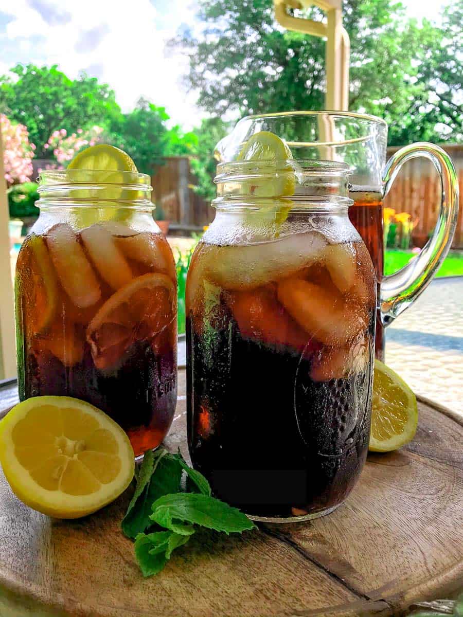 two mason jars full of iced tea with lemon on patio table