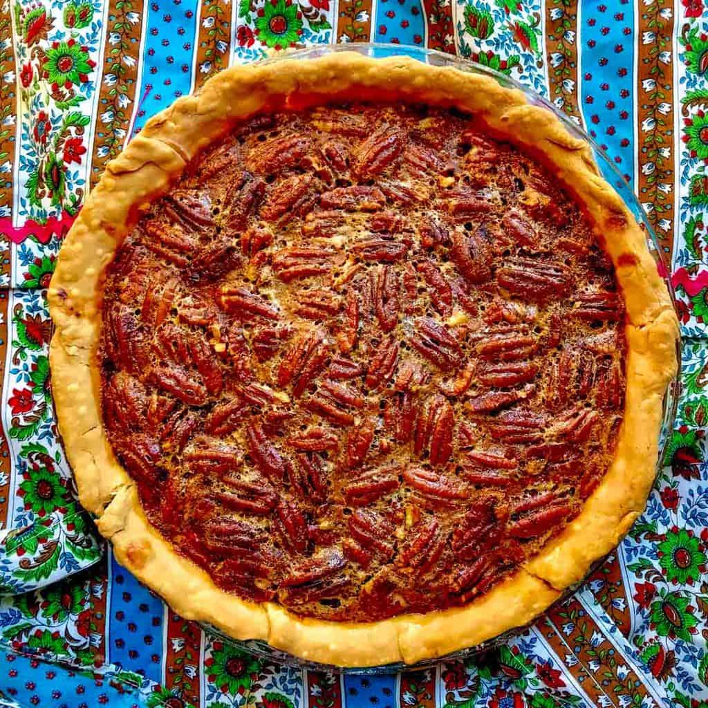 Whole pecan pie on colorful tablecloth