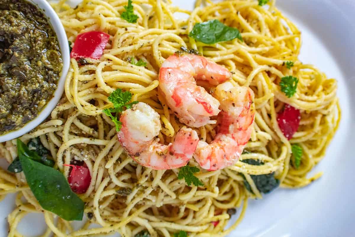 Shrimp on pasta with a side of pesto sauce