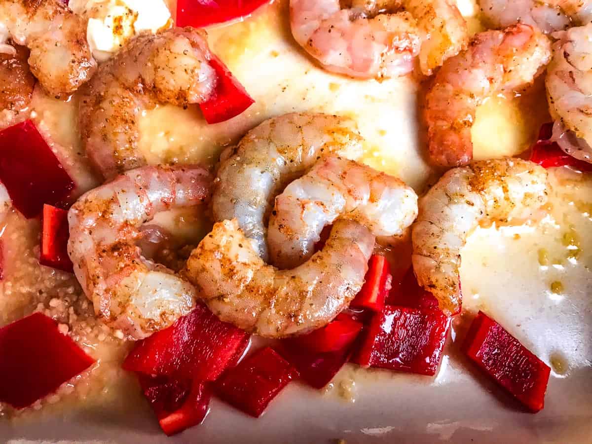 Seasoned shrimp, red bell pepper, garlic and butter in pan.