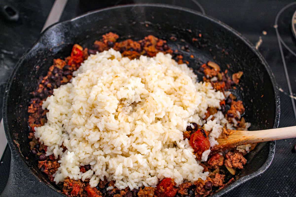 Prepared rice over ground beef in cast iron skillet