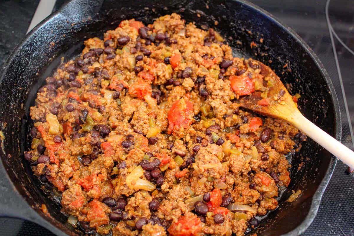 Beef, onions, stewed tomatoes and black beans in cast iron skillet