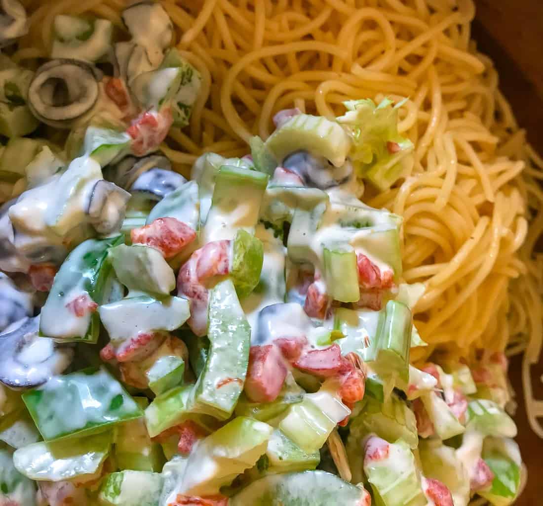 Mayonnaise and vegetables on top of cooked pasta