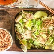 Salad on wooden plate with a side of noodles and sunflower seeds