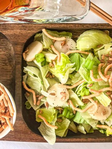 Salad on wooden plate with a side of noodles and sunflower seeds