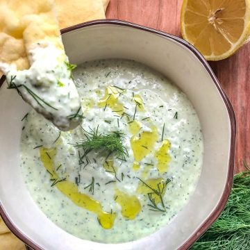 Greek yogurt dip in a bowl with a piece of naan bread dipped