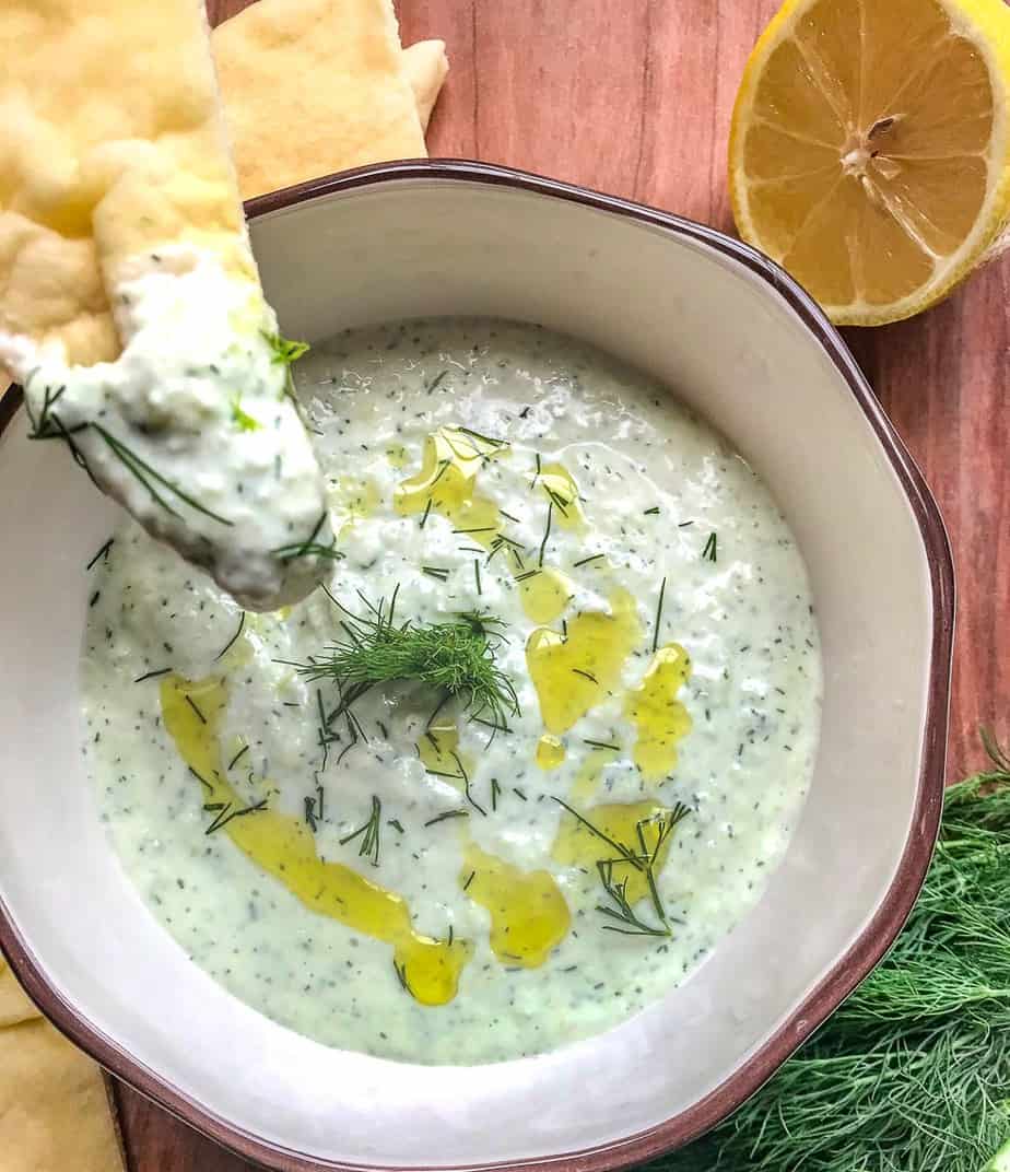 Greek yogurt dip in a bowl with a piece of naan bread dipped